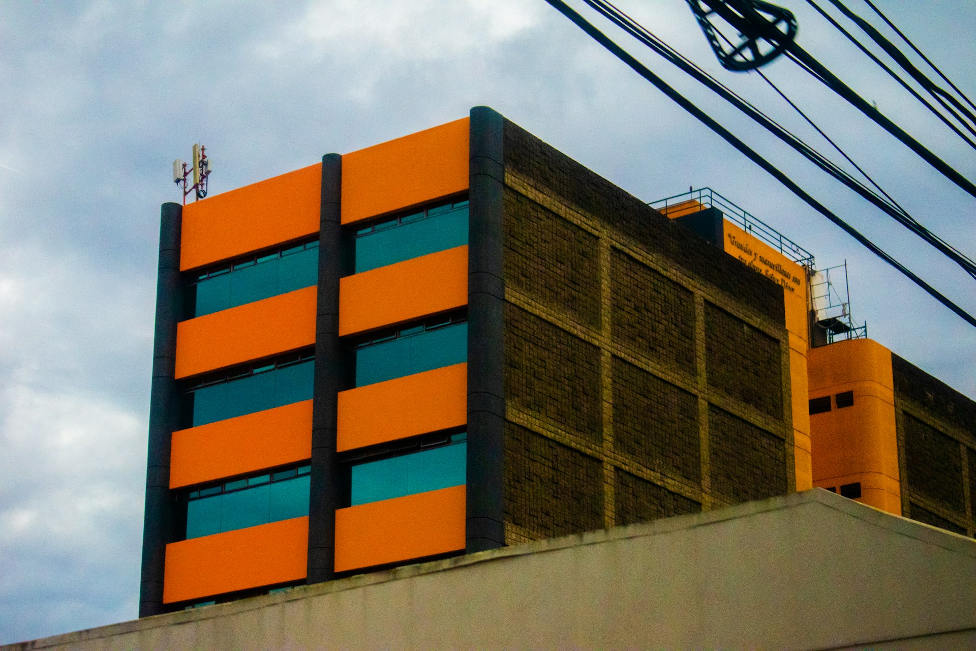 a tall orange and blue building next to power lines